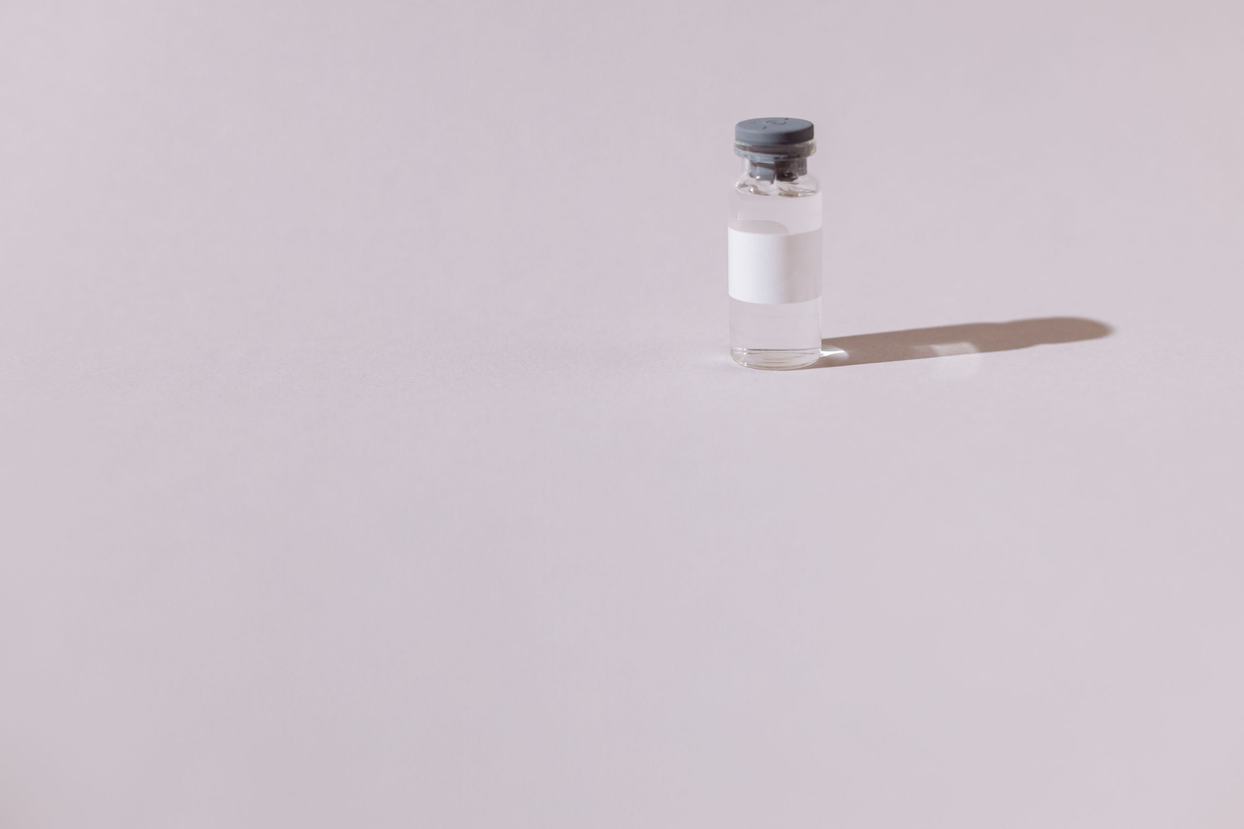A sterile vaccine vial isolated on a minimalist gray background, emphasizing health and medicine.